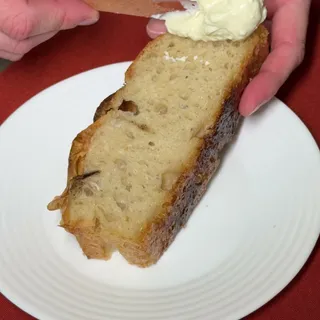 Mão segurando uma fatia grossa de focaccia com uma camada generosa de coalhada seca