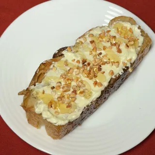 Fatia de focaccia com coalhada seca, mel e castanhas picadas por cima